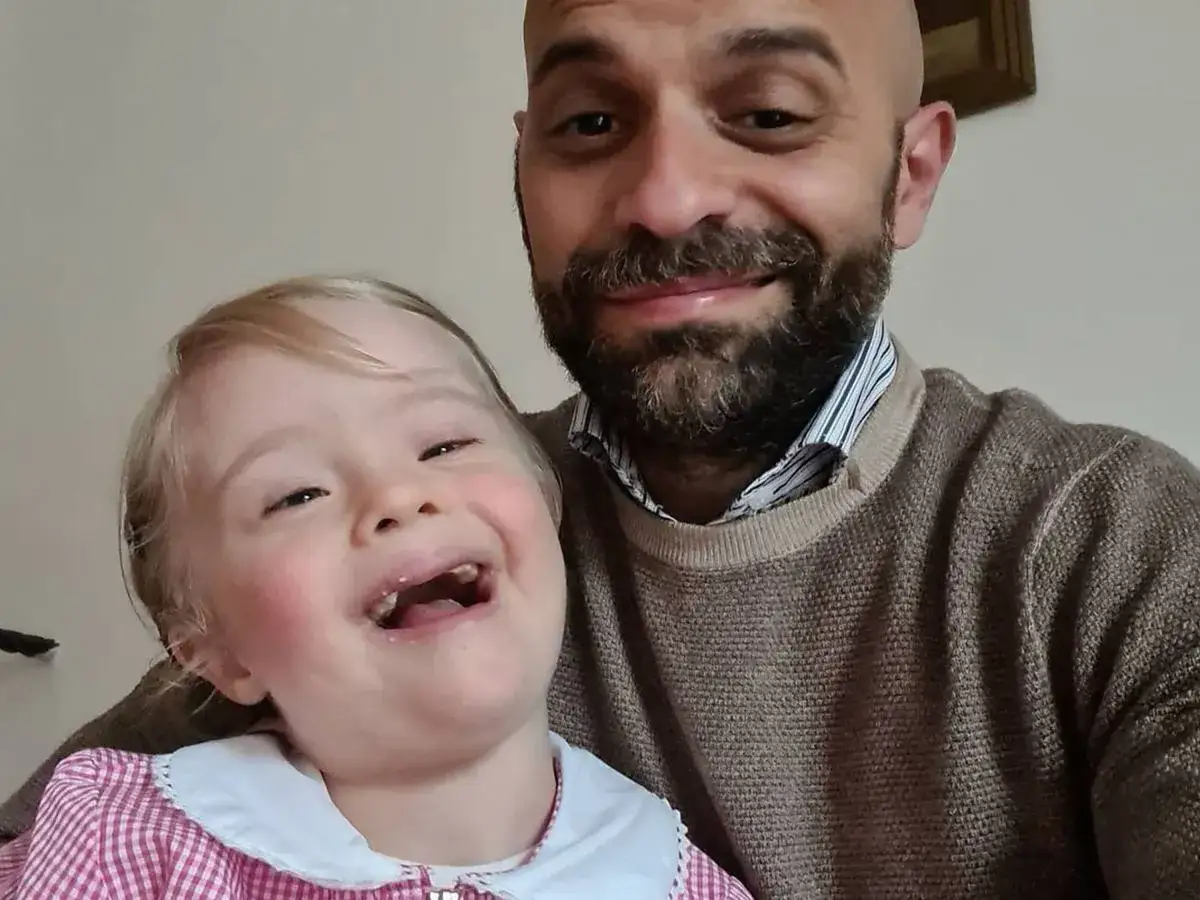 Szczęśliwy ojciec z córką z zespołem Downa. Rozważasz, jak adoptować dziecko z zespołem Downa? To piękna droga.