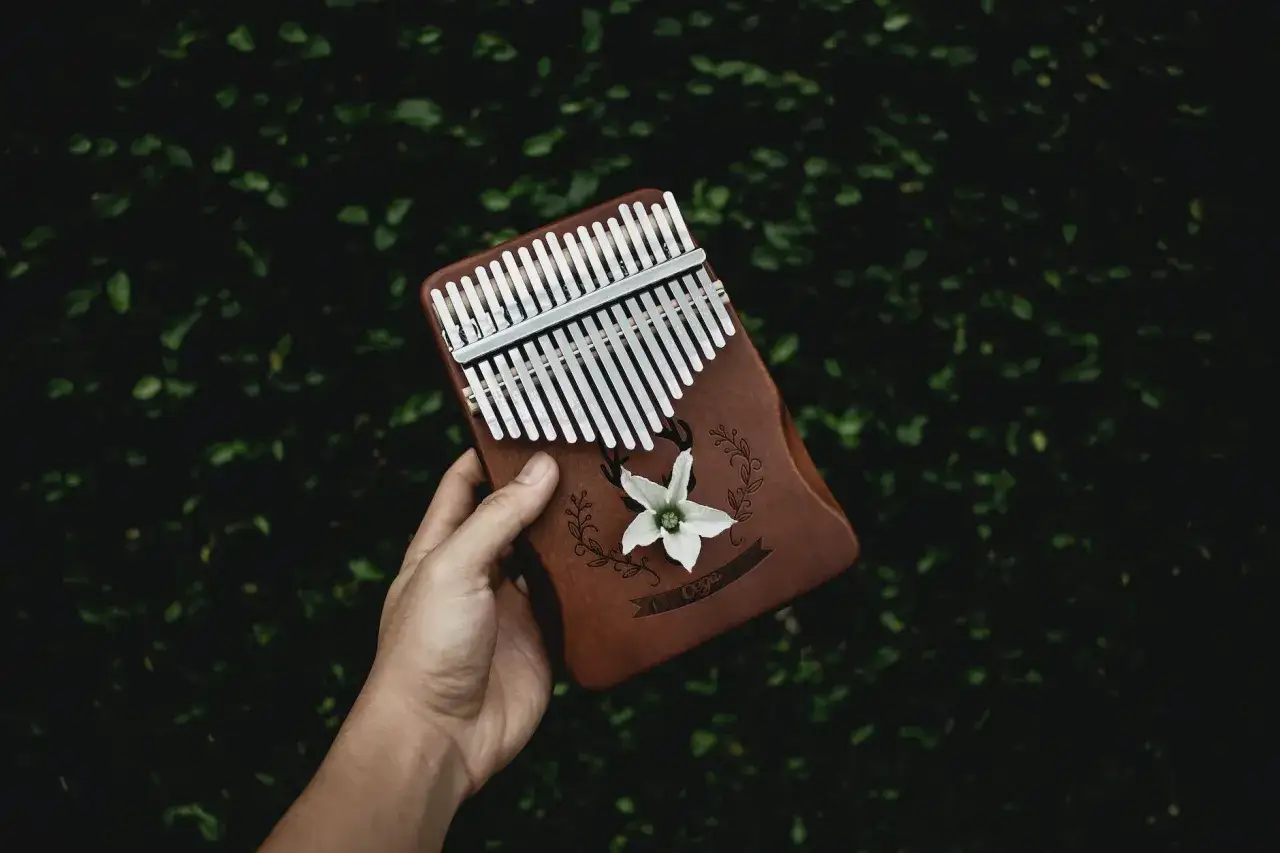 Dłoń trzyma kalimbę z ozdobnym kwiatem i napisem. Dowiedz się, jak grać na kalimbie i twórz magiczne melodie.