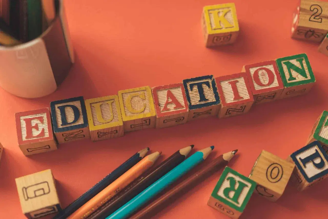 Klocki z literami tworzą napis EDUCATION. Obok leżą kredki i inne klocki, idealne do nauki tekstów po angielsku B2.