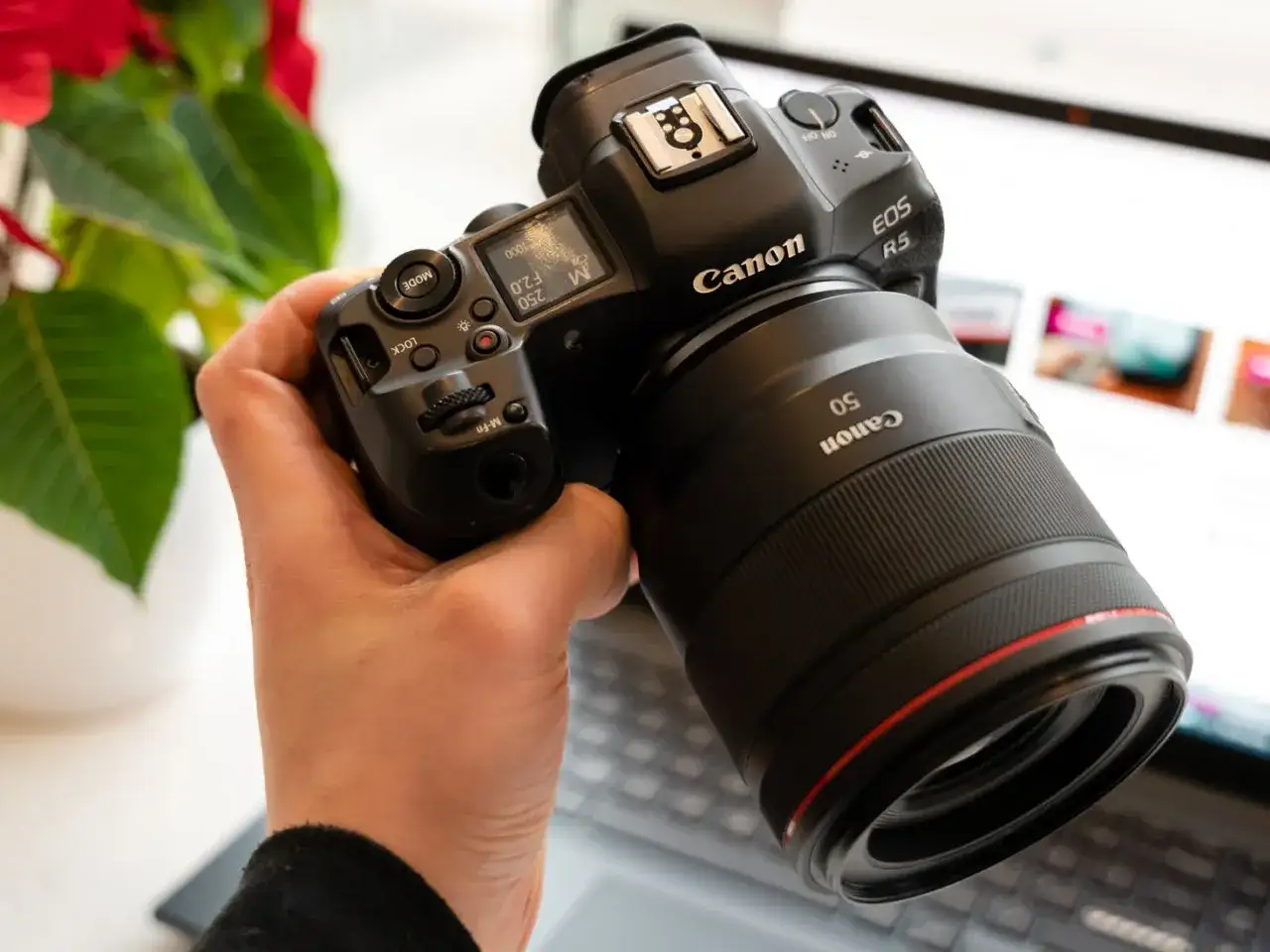 Dłoń trzyma aparat Canon R5 z obiektywem 50mm. Trwa test możliwości sprzętu.