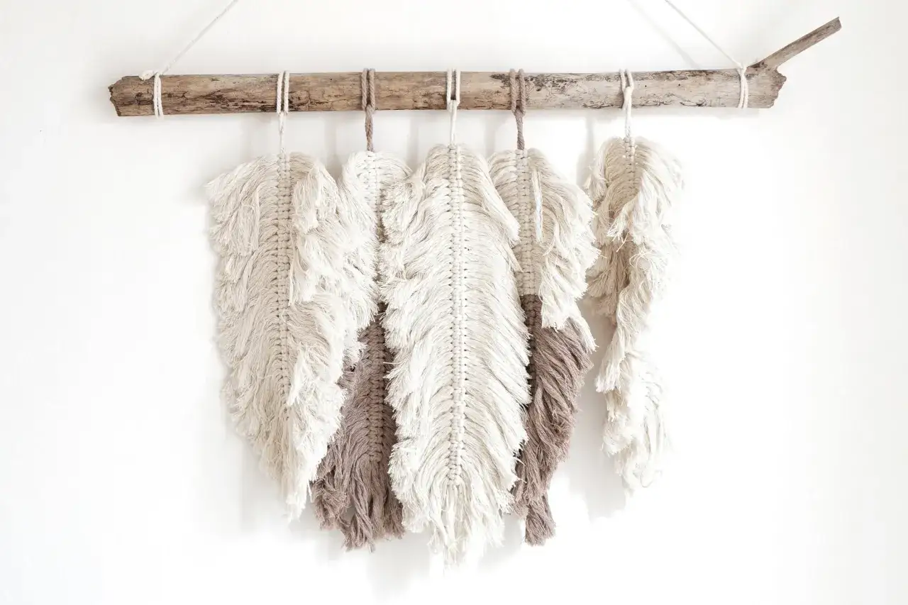 Makrama w kształcie piór, zawieszona na dryfującym drewnie. Inspiracja, jak zrobić liście makrama.