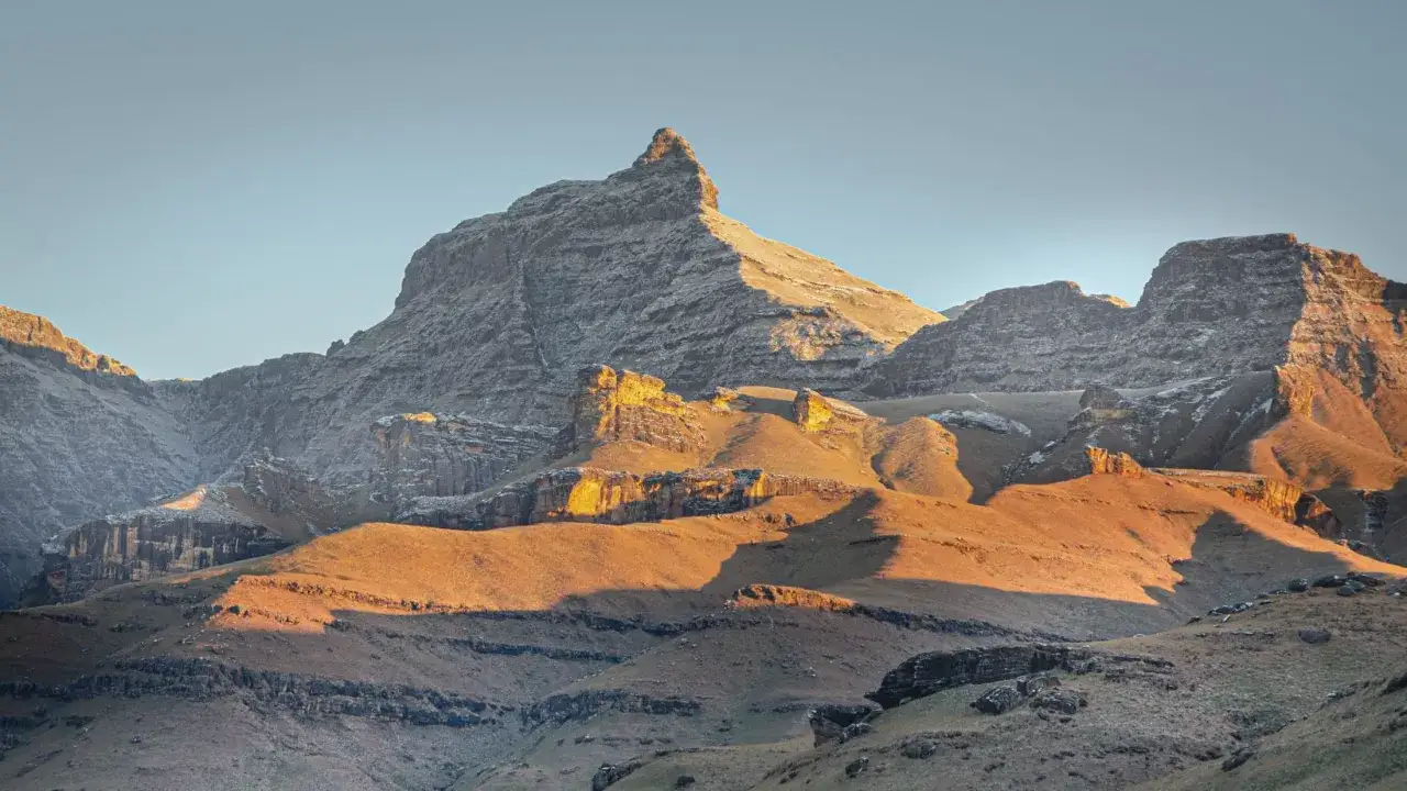 Majestatyczne góry smocze w Afryce oświetlone złotym blaskiem zachodzącego słońca. Ich skaliste zbocza i ostre szczyty przypominają śpiące bestie.