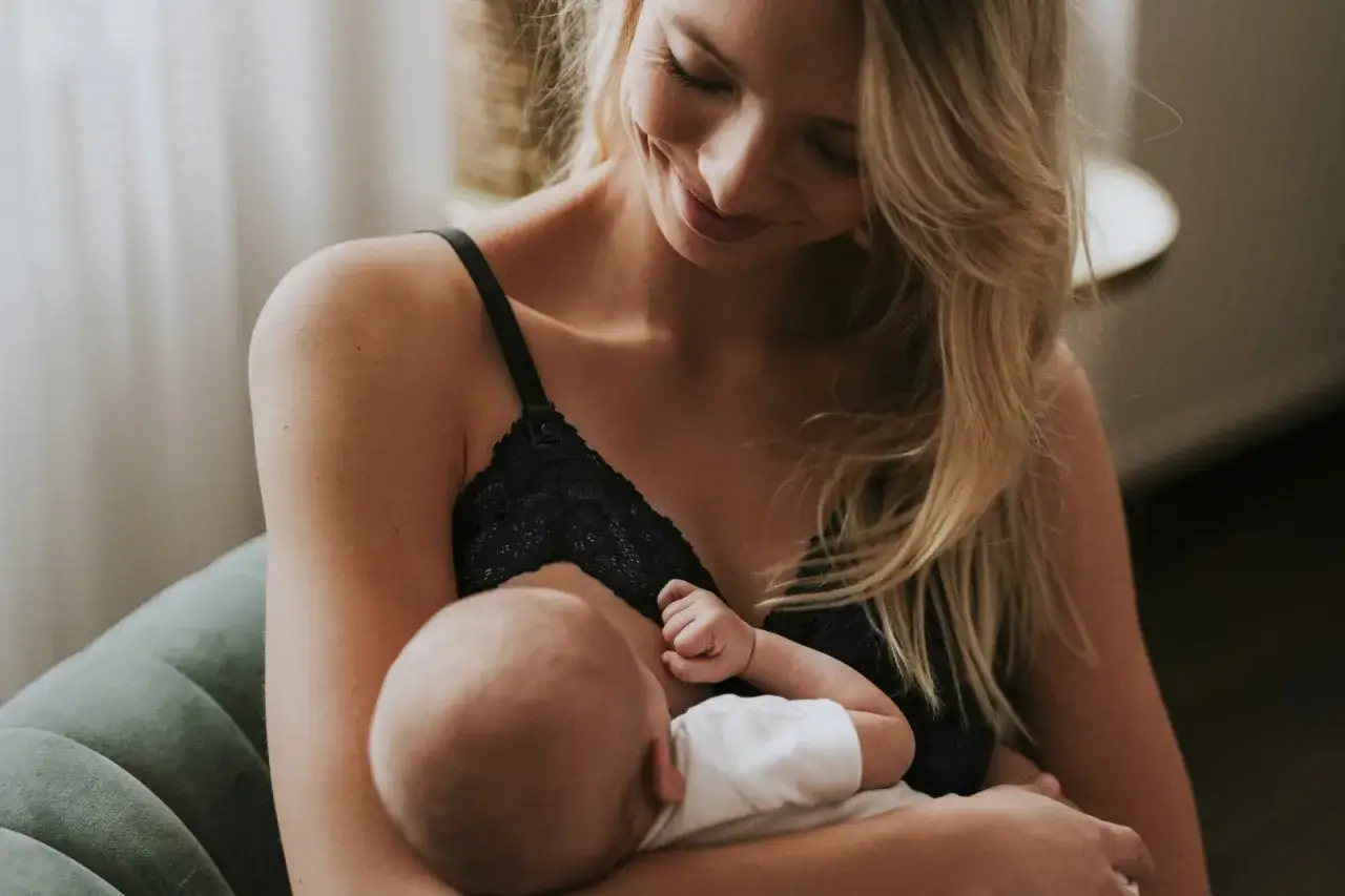 Uśmiechnięta mama karmi piersią swoje dziecko. Delikatne chwile bliskości i miłości.
