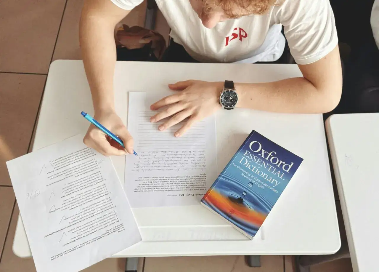Uczeń pisze wypracowanie, a obok leży słownik "Oxford Essential Dictionary". Zastanawia się, co to jest "suffix" i jak go użyć.