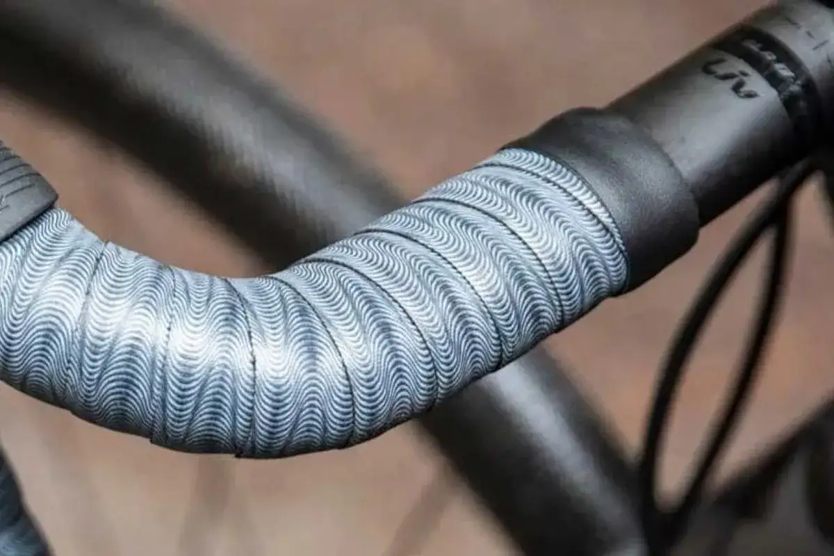 Wyjątkowa owijka na kierownicę roweru z falistym wzorem w odcieniach szarości i bieli.