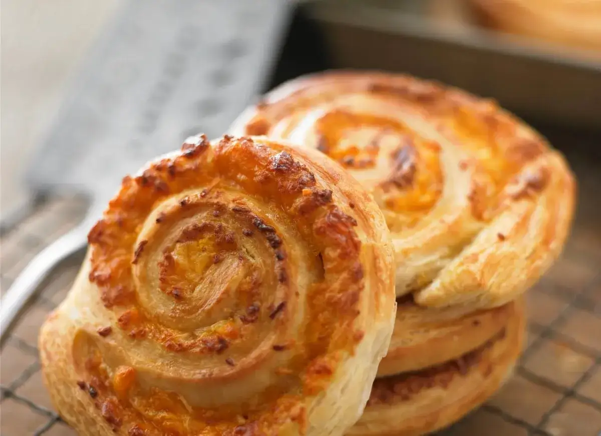 Złociste, chrupiące ciasto francuskie z serem, zwinięte w apetyczne ślimaczki, gotowe do podania.