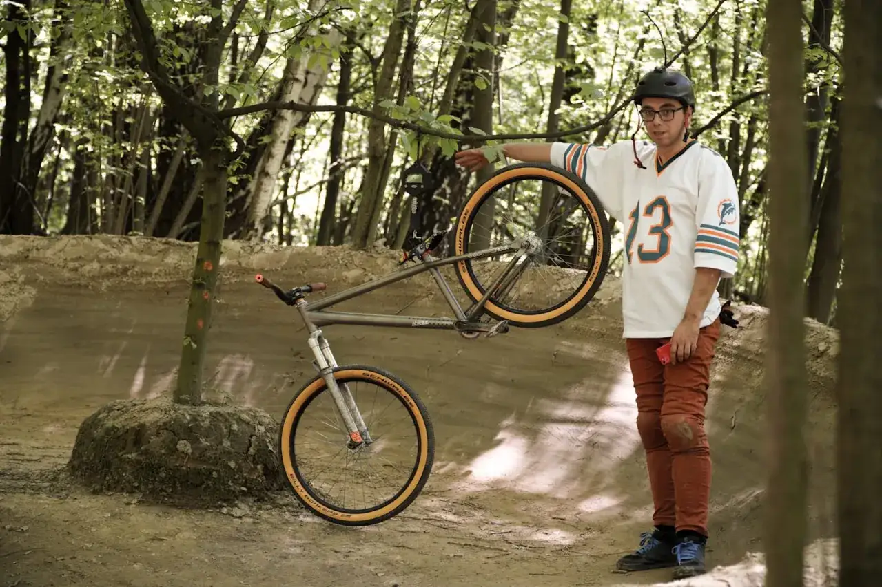 Mężczyzna w koszulce z numerem 13 prezentuje rower, który może być najlżejszym rowerem na świecie.