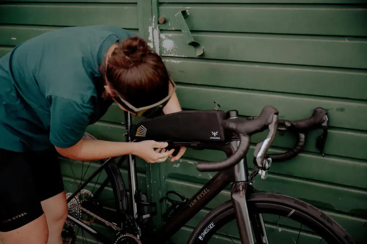 Osoba montuje torbę podsiodłową do roweru. Przygotowania do składania roweru przed wyprawą.