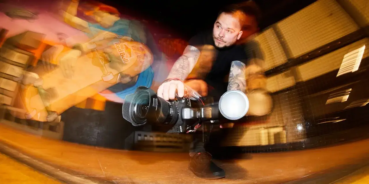 Fotograf z tatuażami łapie ruch deskorolkarza z Red Bulla. Krótki czas naświetlania uchwycił dynamiczną akcję.