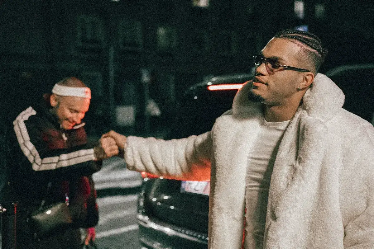 Dwóch mężczyzn wita się na ulicy. Jeden w białym futrze, drugi w dresie. Pijemy za lepszy czas, kto śpiewa?