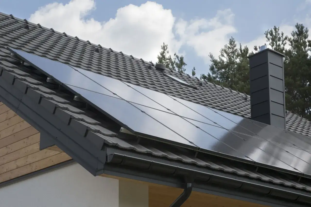 Nowoczesny dach z paneli fotowoltaicznych, szary komin i dachówka. Dom gotowy na zieloną energię.