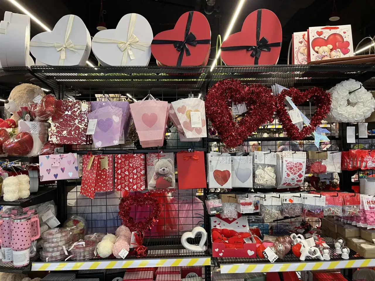 Półki sklepowe z prezentami walentynkowymi: serca, misie, torebki, ozdoby.