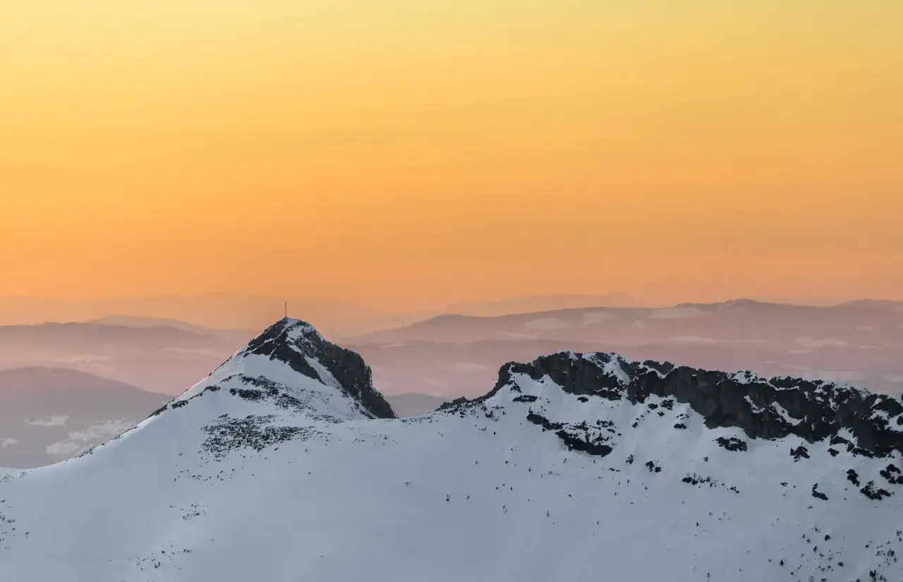 Giewont zimą o zachodzie słońca. Ośnieżone szczyty Tatr w odcieniach pomarańczy i różu.