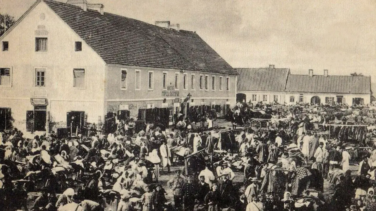 Tłum ludzi na targu w Biłgoraju, jakby żywcem wyjęty z legendy o tym mieście. W tle budynki i stragany.