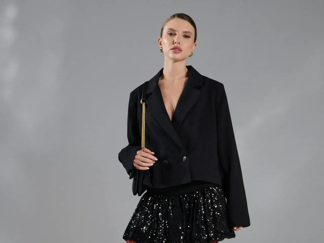 Modelka w czarnej marynarce i błyszczącej spódnicy z cekinami.