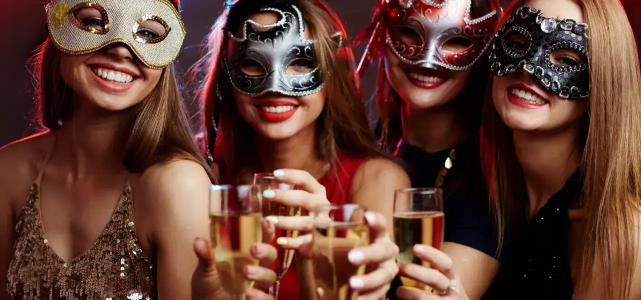 Cztery uśmiechnięte kobiety w maskach bawią się na Sylwestrze w Wiśle, wznosząc toasty szampanem.
