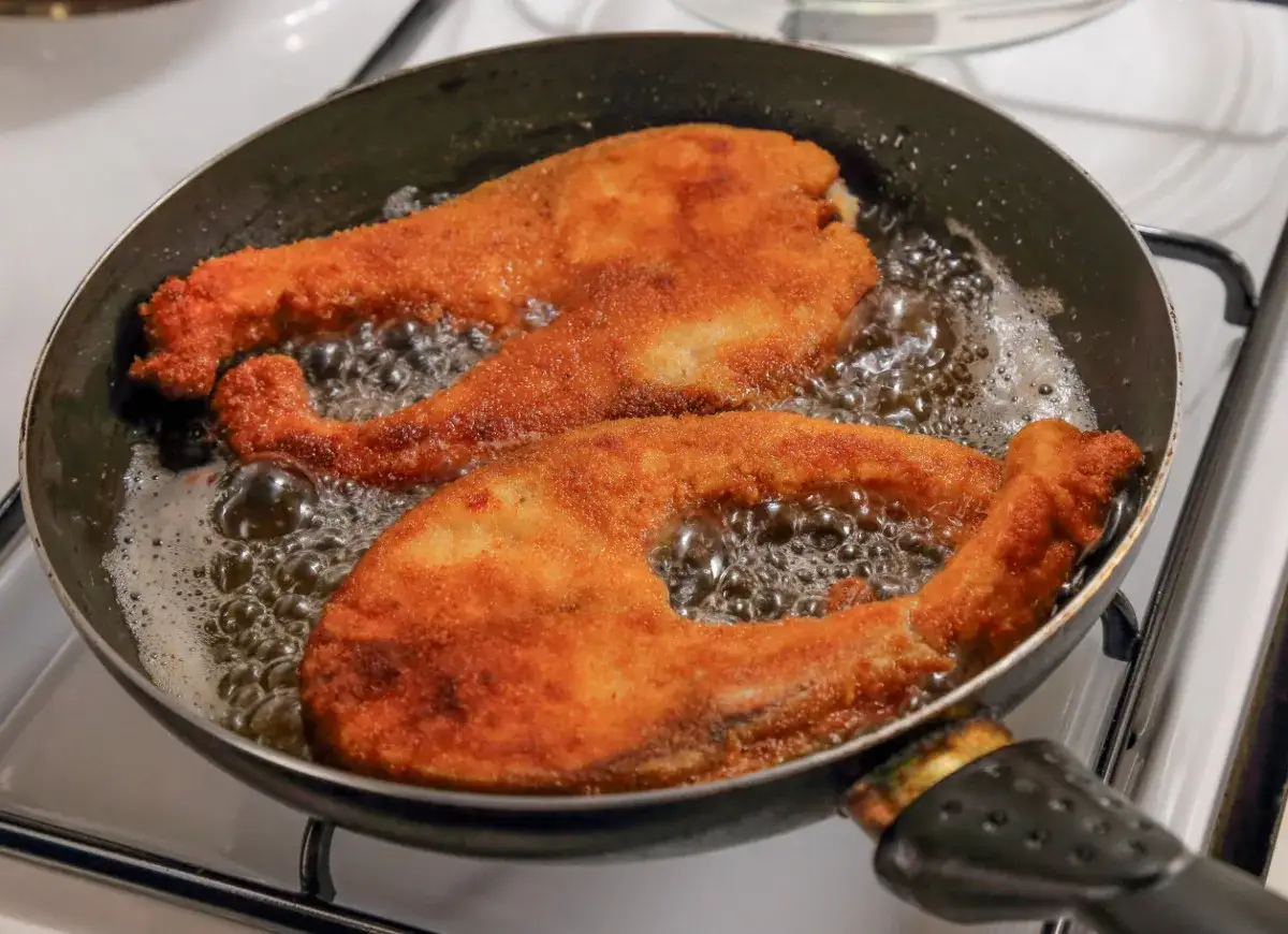 Smażone kawałki ryby w panierce bulgoczą na patelni. Tak właśnie robi się smrodek na ryby, by był chrupiący i złocisty.