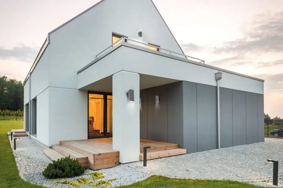 Nowoczesne oświetlenie elewacji podkreśla architekturę domu. Lampy ścienne i stojące tworzą przytulną atmosferę.