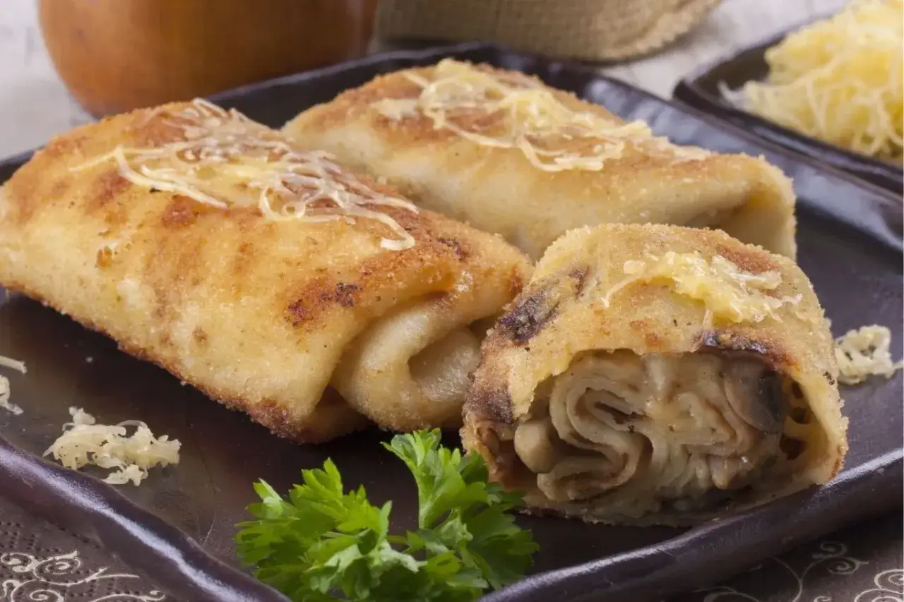 Idealne co na obiad w poniedziałek: złociste krokiety z pieczarkami i serem, posypane startym parmezanem, udekorowane natką pietruszki.