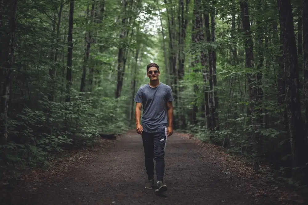 man walking under forest