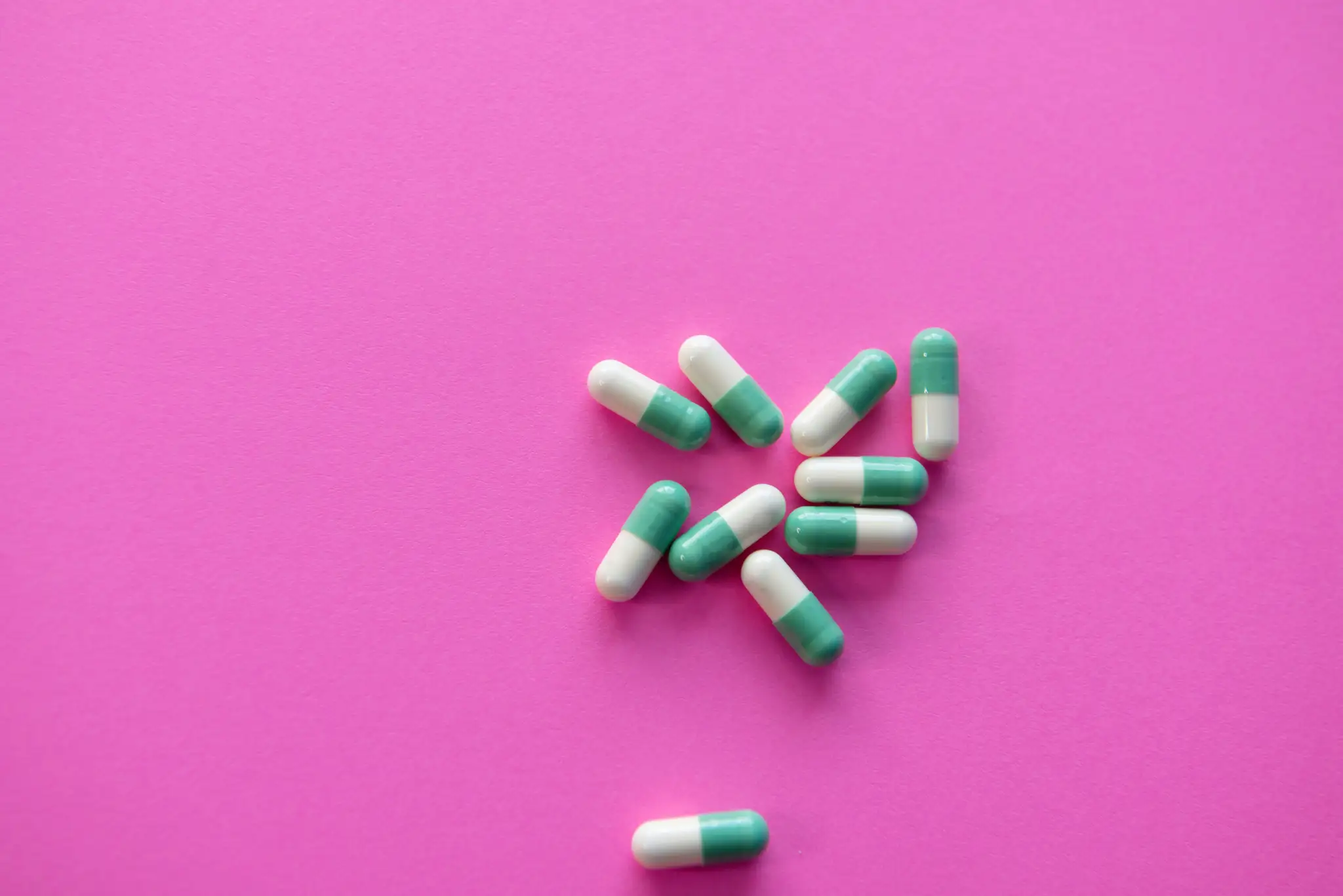 white and blue medication pill on pink textile