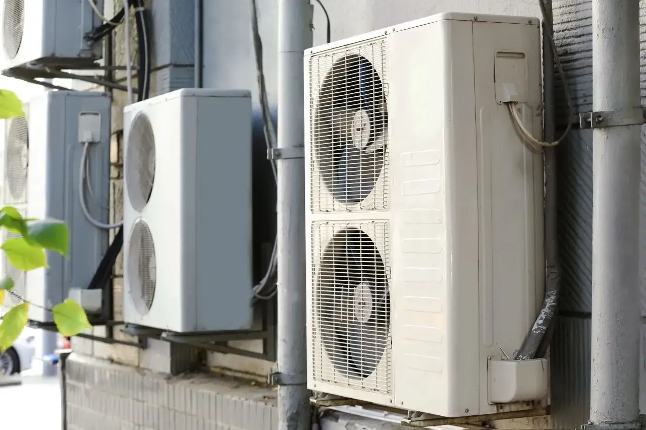 Kilka jednostek zewnętrznych klimatyzacji zamontowanych na ścianie budynku.