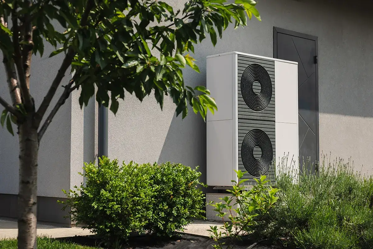 Pompa ciepła 16 kW, idealna do ogrzewania domu o powierzchni do 160 m², stoi obok budynku, otoczona zielenią.