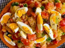 Ensalada campera con patatas, huevos duros, tomate, pimiento y aceitunas. Ingredientes frescos y sabrosos.