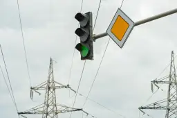 Zielone światło na sygnalizatorze i znak pierwszeństwa wskazują, że można wykonać zawracanie na skrzyżowaniu z sygnalizacją.