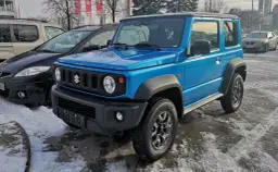 Niebieski Suzuki Jimny 2026 gotowy na zimowe przygody, zaparkowany na śniegu obok innych samochodów.