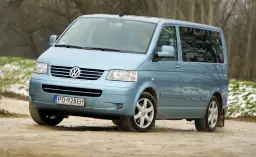 Jasnoniebieski Volkswagen Transporter T5 na drodze gruntowej.