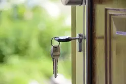 Klucz w zamku drzwi wejściowych. Zastanawiasz się, ile kosztuje wymiana zamka w drzwiach wejściowych?