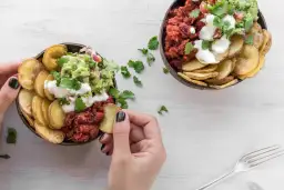 Dwie miski z guacamole, fasolą i chipsami z ziemniaków. Ziemniaki kcal w zdrowej odsłonie.