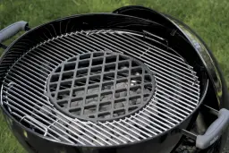 Grill ogrodowy z rusztem i węglem drzewnym.