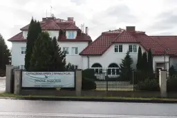 Budynek z czerwonym dachem i banerem "Zielone Wzgórze".
