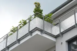 Nowoczesny balkon z ażurową balustradą i zielenią. Solidna hydroizolacja balkonu zapewnia trwałość i komfort użytkowania.