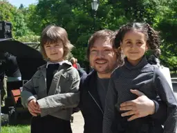 Mietek Szczęśniak z żoną i dziećmi na planie filmowym. Uśmiechnięty ojciec obejmuje córkę, obok stoi druga pociecha.