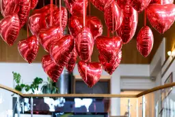 Mnóstwo błyszczących, czerwonych balonów w kształcie serc i owali, tworzących romantyczne ozdoby walentynkowe diy.