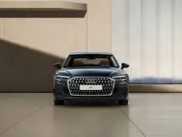 Elegancki, ciemnoniebieski Audi A8 2025 z brązowym wnętrzem prezentuje się na tle nowoczesnej architektury.