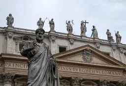 Kamienna postać z kluczem w dłoni, na tle bazyliki. Czy mantry są niebezpieczne? Ta rzeźba nie daje odpowiedzi.