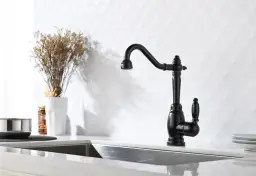 Elegancka, czarna bateria retro w kuchni. Obok suszone kwiaty i słoiczek z przyprawami.
