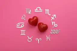 Dwa czerwone serca otoczone srebrnymi symbolami zodiaku. Dziś horoskop na dziś Waga miłosny zapowiada gorące uczucia.