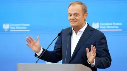 Donald Tusk przemawia, gestykulując. W tle logo Kancelarii Premiera. Czy zastanawiasz się, ile zarabia Tusk miesięcznie?
