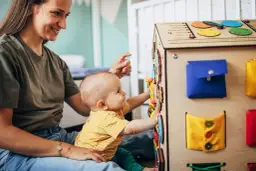 Maluch z radością odkrywa tablicę manipulacyjną. Od jakiego wieku taka zabawka? Od momentu, gdy dziecko zaczyna siedzieć i chwytać.