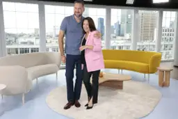 Ewa Drzyzga i Marcin Borowski stoją objęci na tle okien z widokiem na miasto.