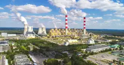 Ogromna elektrownia Bełchatów z kominami i chłodniami, emitująca białe kłęby pary. Zastanawiasz się, ile węgla spala elektrownia Bełchatów?