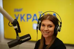 Uśmiechnięta prezenterka w słuchawkach przed mikrofonem. Na tle logo RMF MAXXX, które można usłyszeć na tej samej częstotliwości.