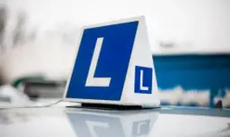 Tablica z literą "L" na dachu samochodu. Zastanawiasz się, ile kosztuje prawo jazdy na raty?