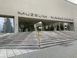 Wejście do Muzeum Narodowego w Poznaniu z szerokimi kamiennymi schodami i napisem na fasadzie.