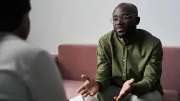 Un homme barbu en chemise verte et lunettes discute avec une personne hors champ, évoquant une rupture conventionnelle.